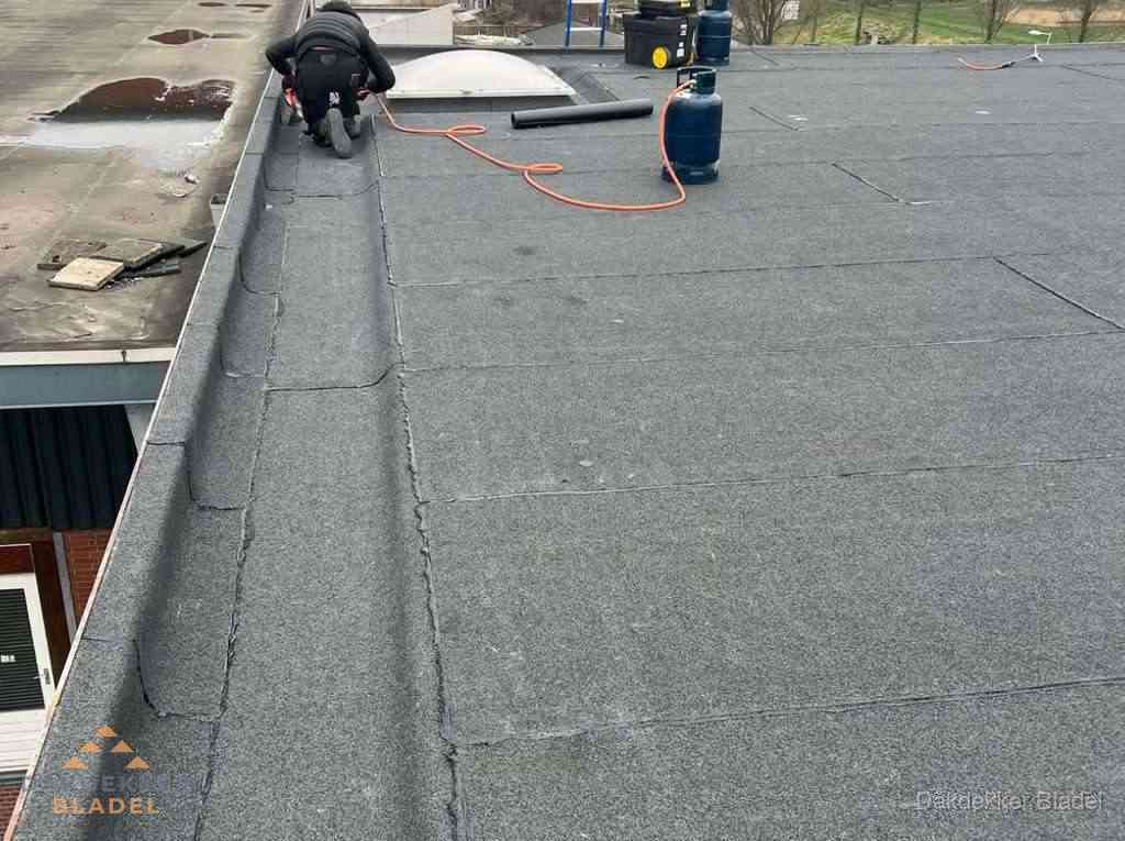 Dakdekker repareert bitumen dakbedekking op groot plat dak in Bladel